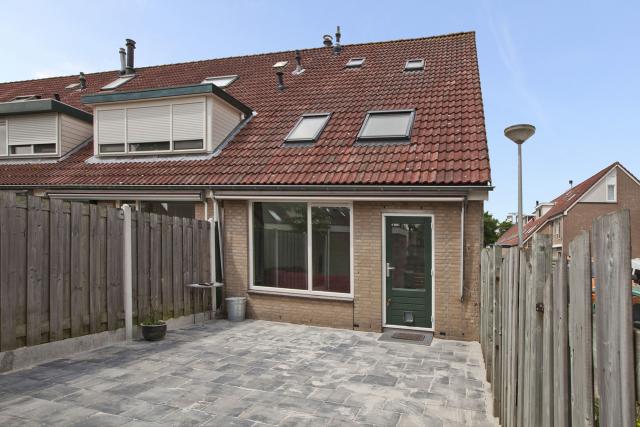 de tuin geheel bestraat met licht grijze getrommelde stenen